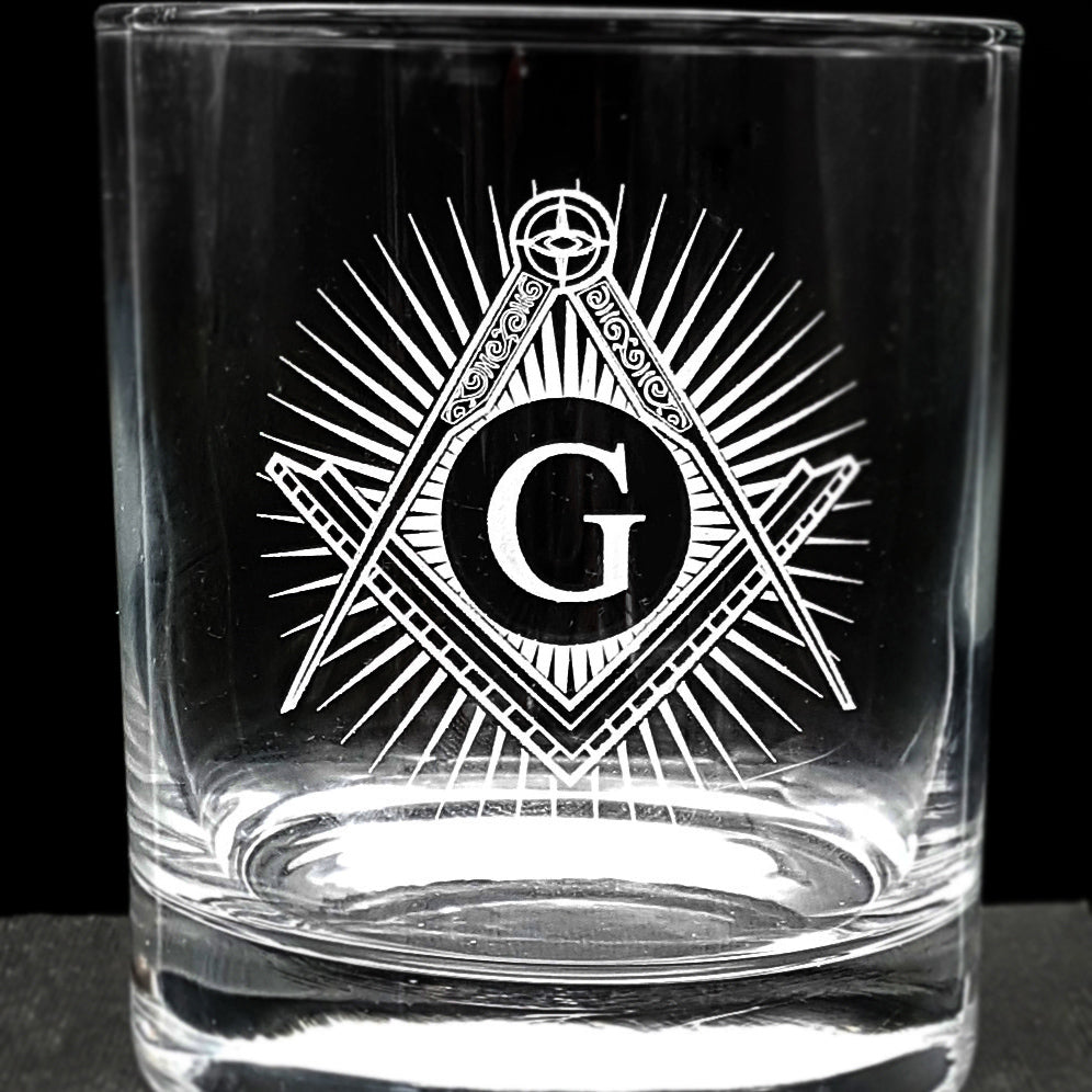 Close up of Masonic compass and set square with G and star burst background on a glass tumbler.