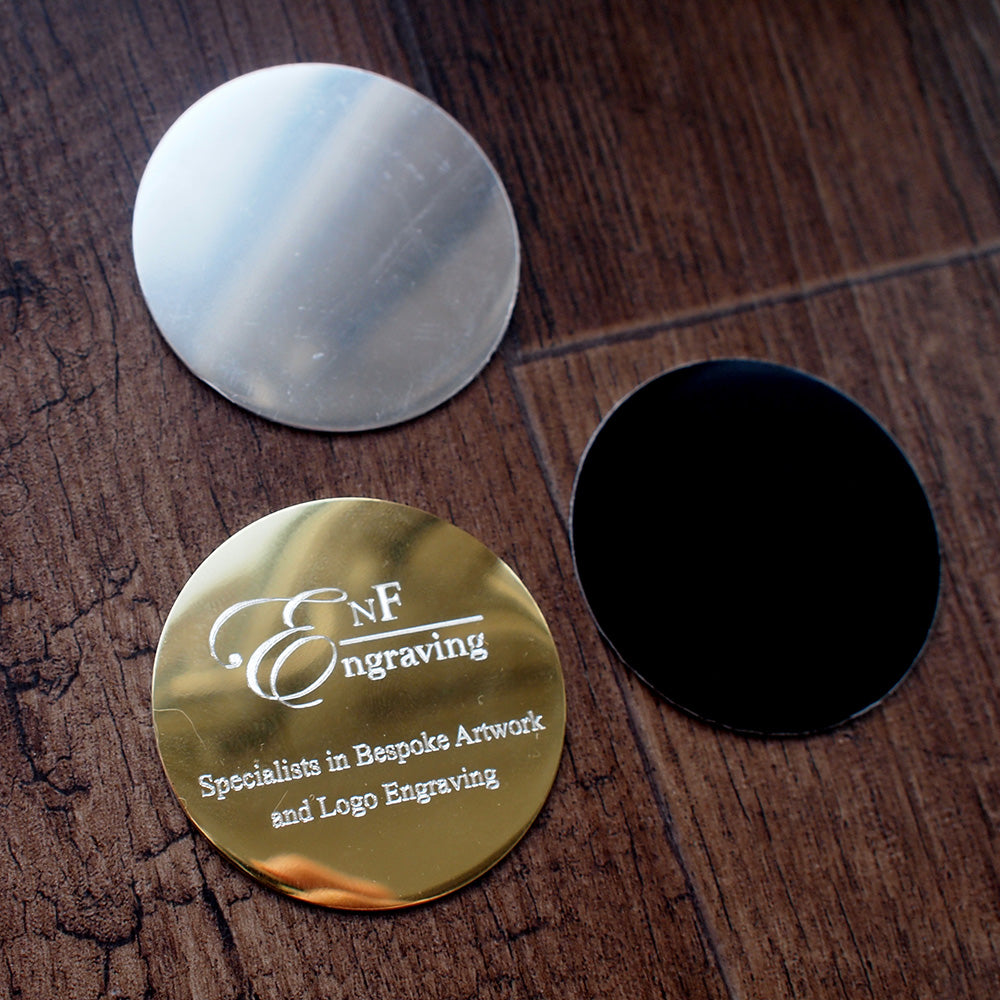 Gold, silver, and black round plaques on a wooden surface background with 'ENF Engraving' branding.