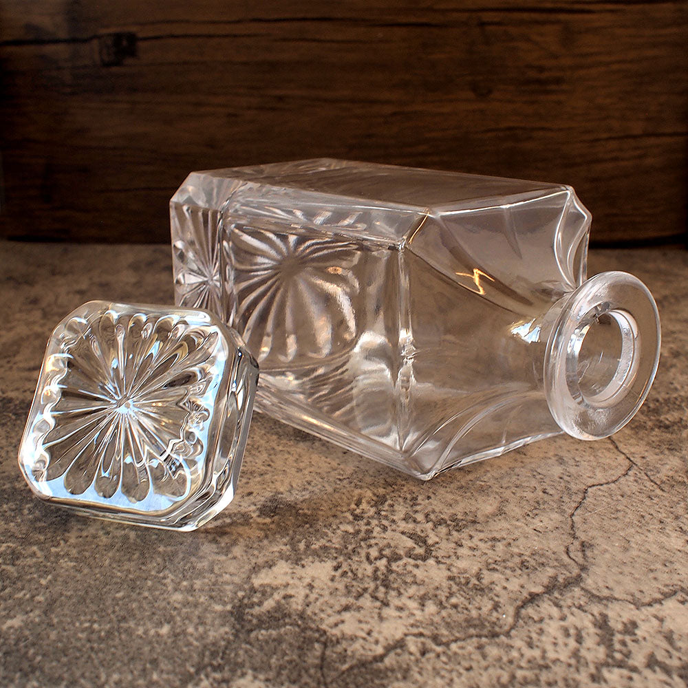 square spirits decanter on its side with stopper removed and displayed nearby showing the cut details on the top of the stopper