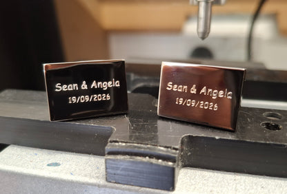 Two engraved cufflinks on a metal engraving machine
