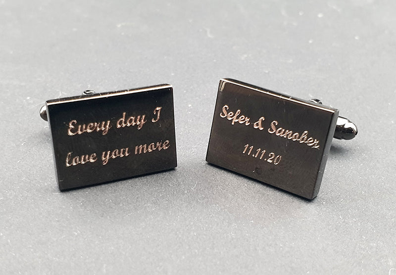 Set of black rectangular cufflinks with engraved text