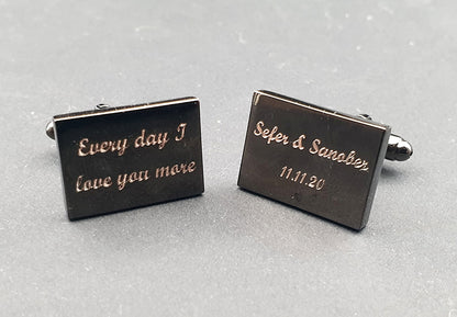 Set of black rectangular cufflinks with engraved text