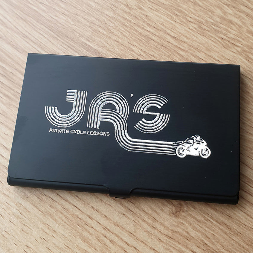 Black business card with 'JRS Private Cycle Lessons' text and motorcycle graphic engraved