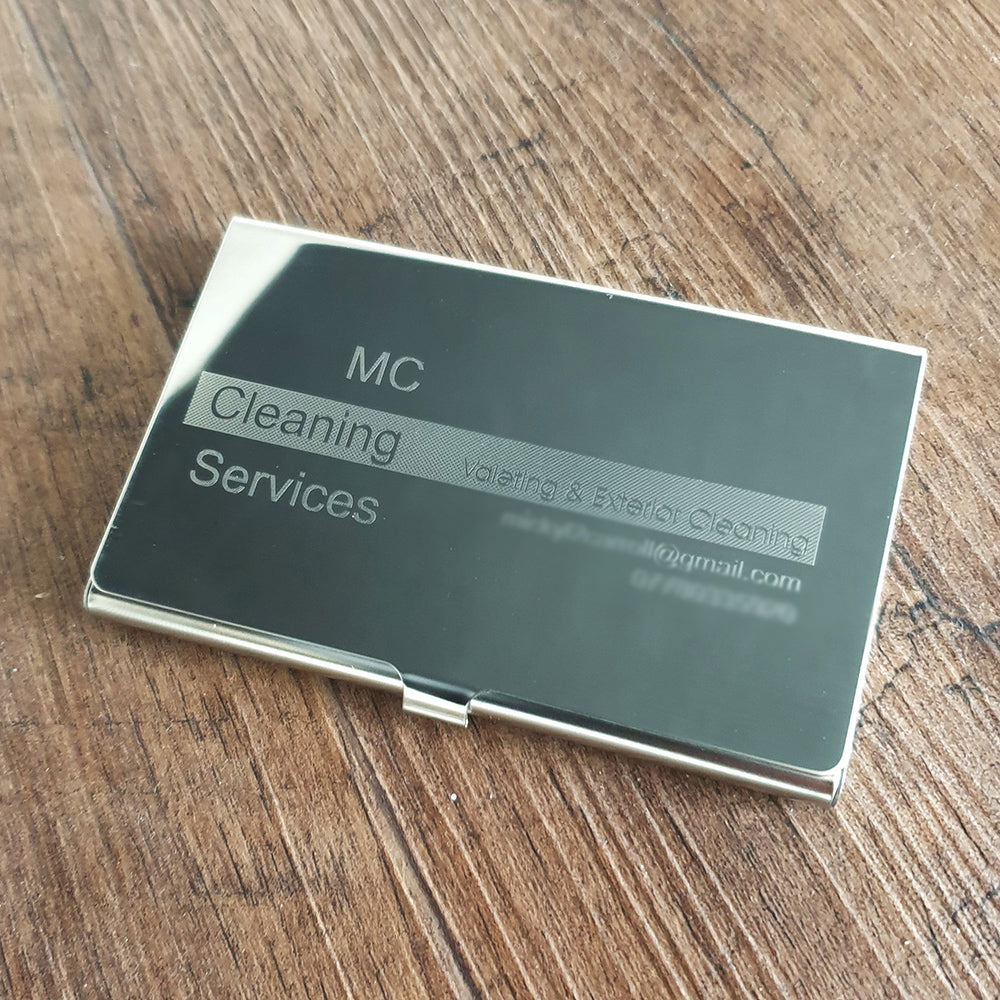 Steel Business card holder with 'MC Cleaning Services' on a wooden surface background