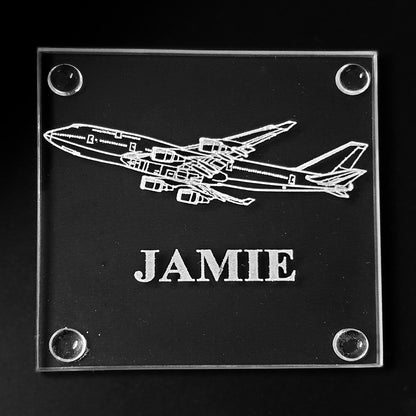 Glass coaster with 747 airplane design and 'JAMIE' engraving on a black background