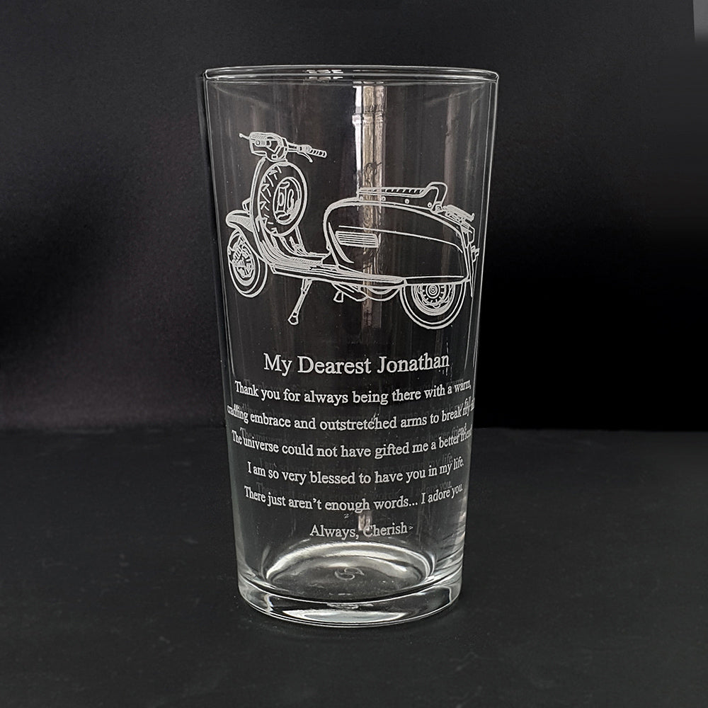 Lamb scooter artwork with a large amount of text engraved below on the front of a beer glass
