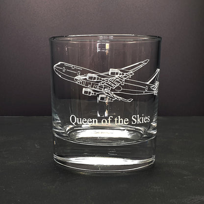 Clear glass tumbler with 747 artwork airplane engraving and 'Queen of the Skies' text on a dark background