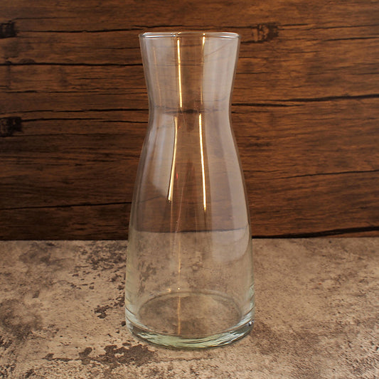 Clear glass carafe on a stone surface with a wooden background