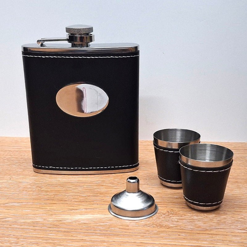 Black Leather Hip Flask with Tot Cups and Funnel on a Wood Surface