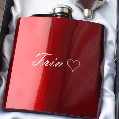 Red flask with 'Trin' and a heart engraved on it, placed in a box.
