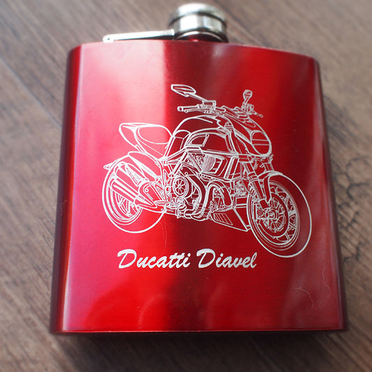 Red hip flask with Diavel Motorcycle artwork engraving on a wooden surface