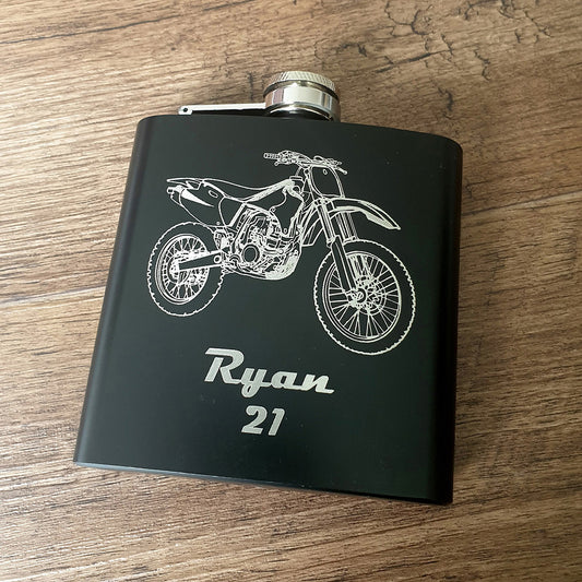 Black flask with motocross motorcycle design and 'Ryan 21' text on a wooden surface