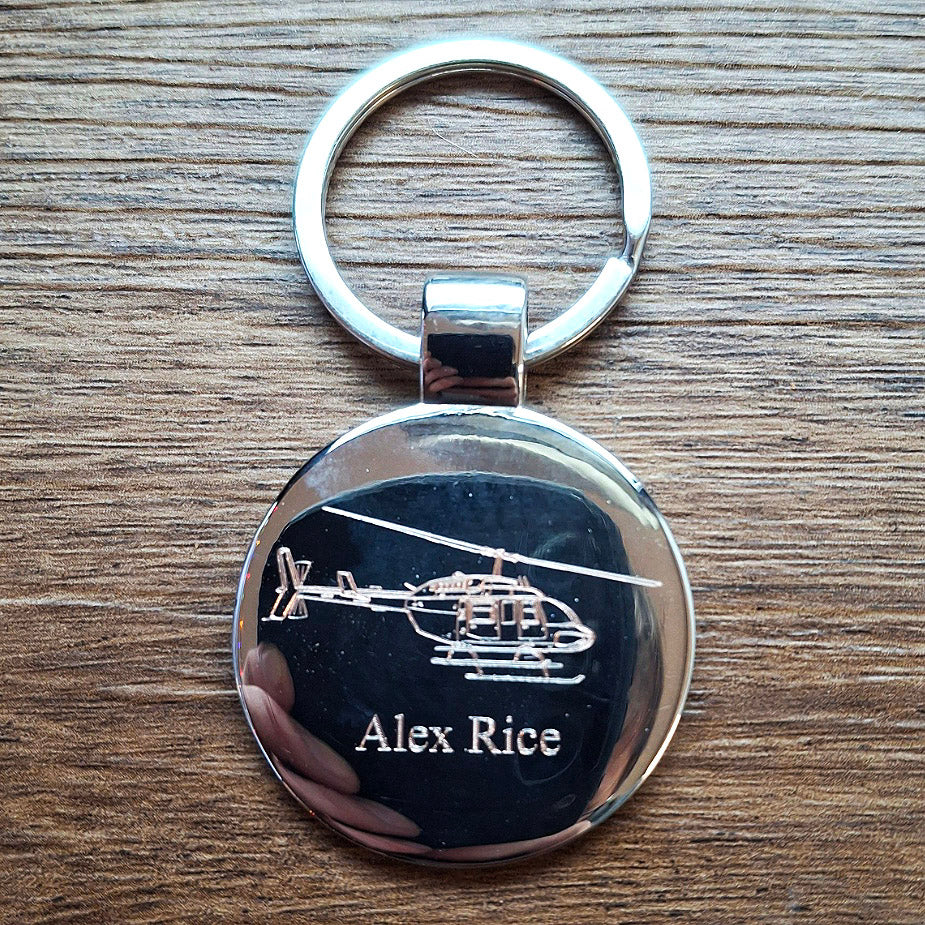 Round Keyring with bell long ranger helicopter engraving and 'Alex Rice' text on a wooden surface