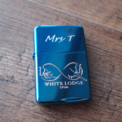 Blue lighter with 'White Lodge Stud' branding on a wooden surface