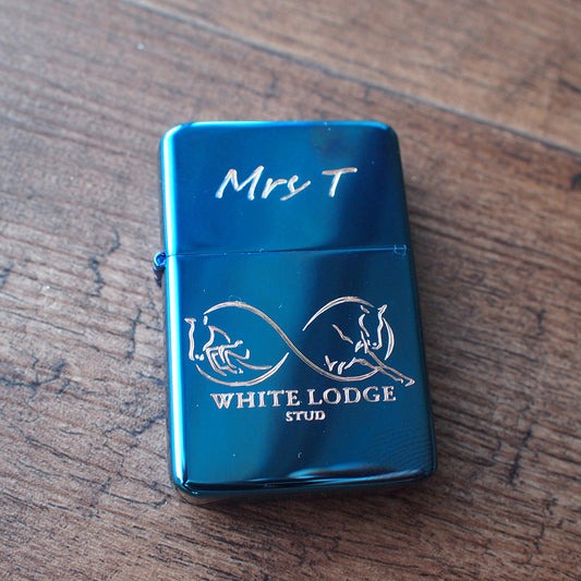 Blue lighter with 'White Lodge Stud' branding on a wooden surface