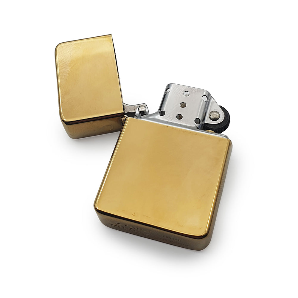 Brass petrol lighter with open lid on a white background