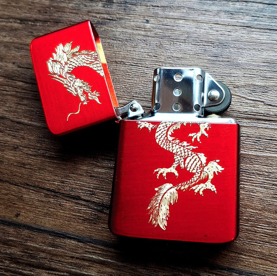 open Red petrol lighter with dragon design on a wooden surface background