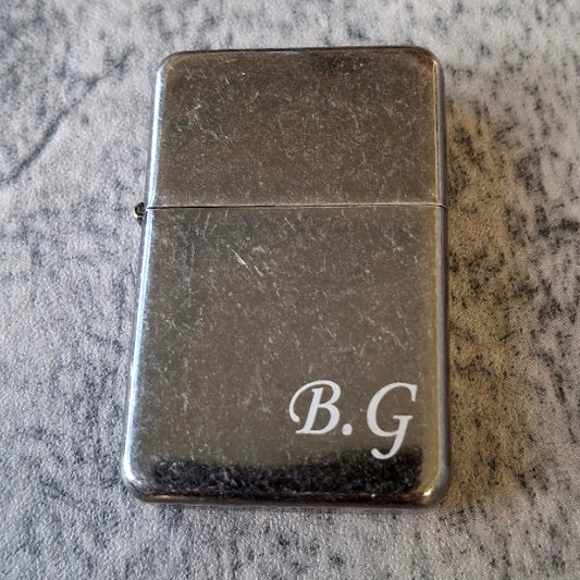 Silver vintage lighter with BG initials engraved in the bottom left.
