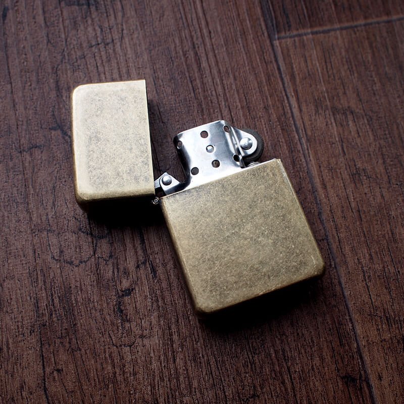 Open vintage style brass petrol lighter on wood background