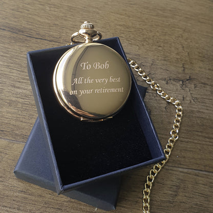 Gold pocket watch with engraved message in a blue box on a wooden surface background