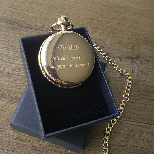 Gold pocket watch with engraved message in a blue box on a wooden surface background