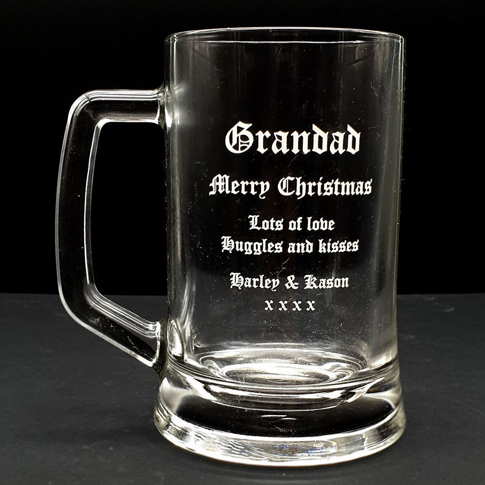 Clear glass beer mug with engraved Christmas message for grandad on a black background