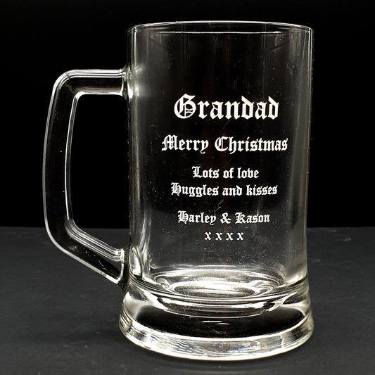 Clear glass beer mug with engraved Christmas message for grandad on a black background