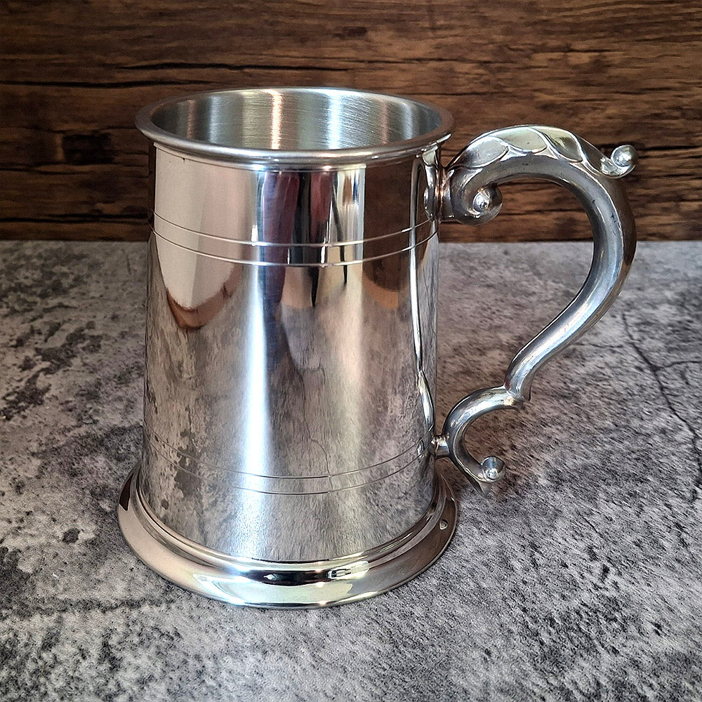 Pewter Tankard with two sets of embossed lines and ornate handle.