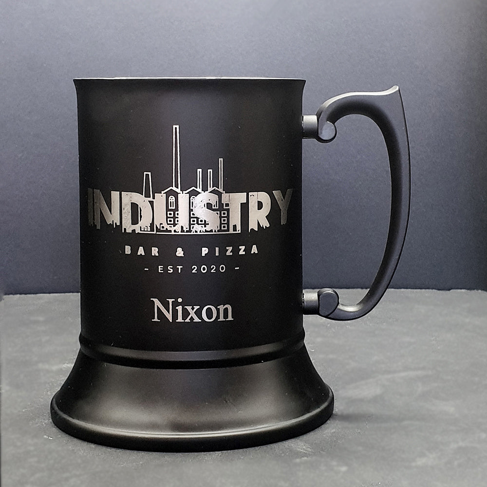Black mug with 'Industry Bar & Pizza' and 'Nixon' branding on a gray background
