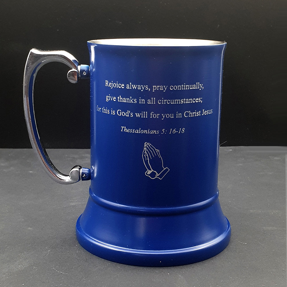 Blue mug with a motivational quote and prayer hands symbol on a dark background