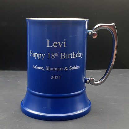 Blue mug with engraved text on a gray surface and black background
