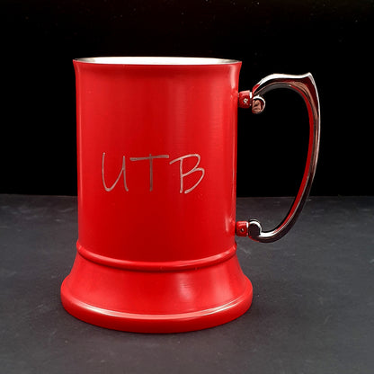 Red steel mug with 'UTB' engraving on a dark surface