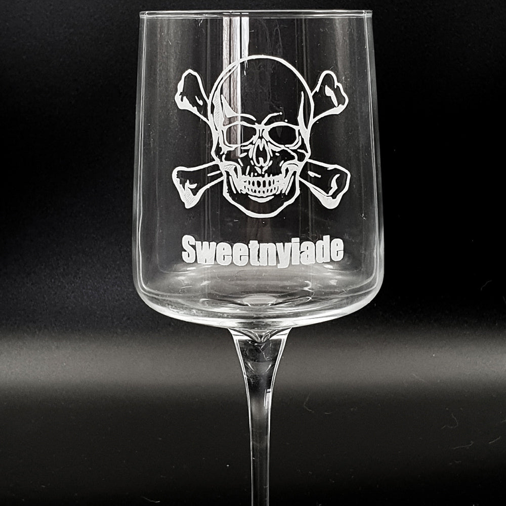 Clear wine glass with skull and crossbones design and 'Sweetmylade' on a black background