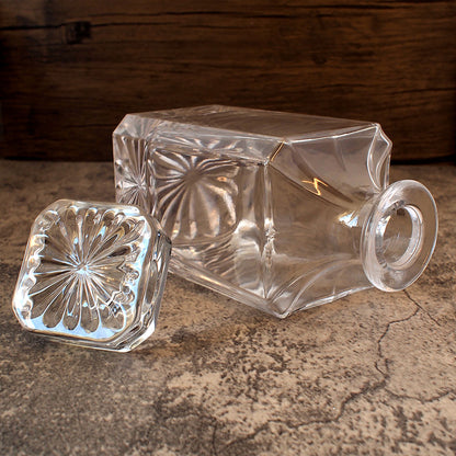 square spirits decanter on its side with stopper removed and displayed nearby showing the cut details on the top of the stopper