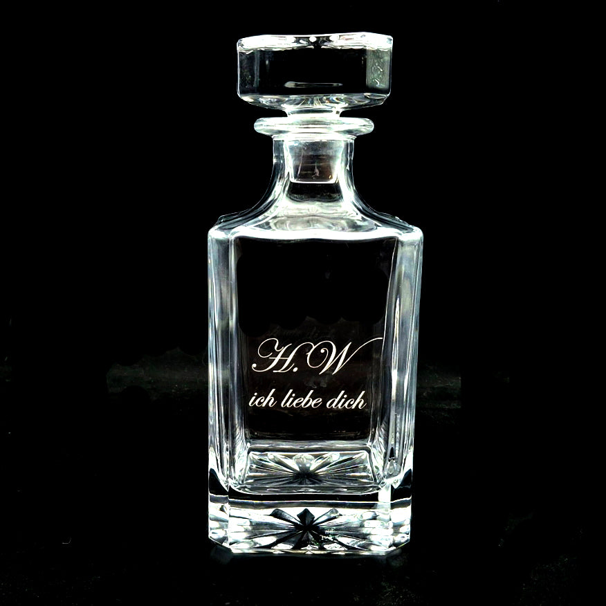 Clear glass square plain decanter with engraved text on a black background