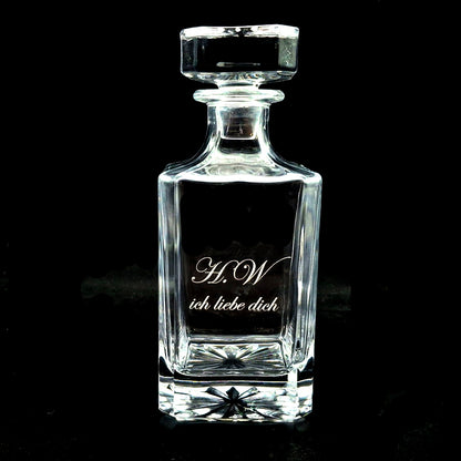 Clear glass square plain decanter with engraved text on a black background