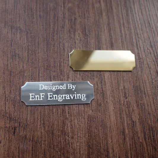 2 Plaques, silver and gold engraving plate with 'Designed By EnF Engraving' text on a wooden surface