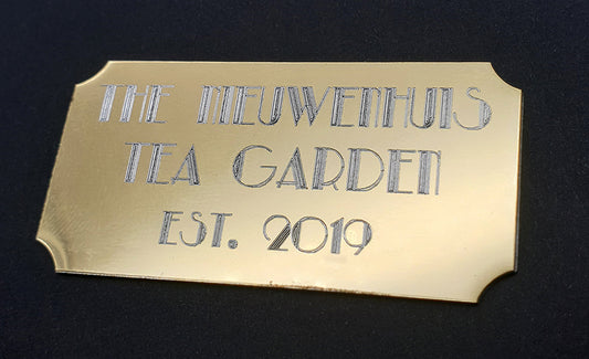 Gold plaque with 'The Nieuwenhuis Tea Garden Est. 2019' text in on a black background