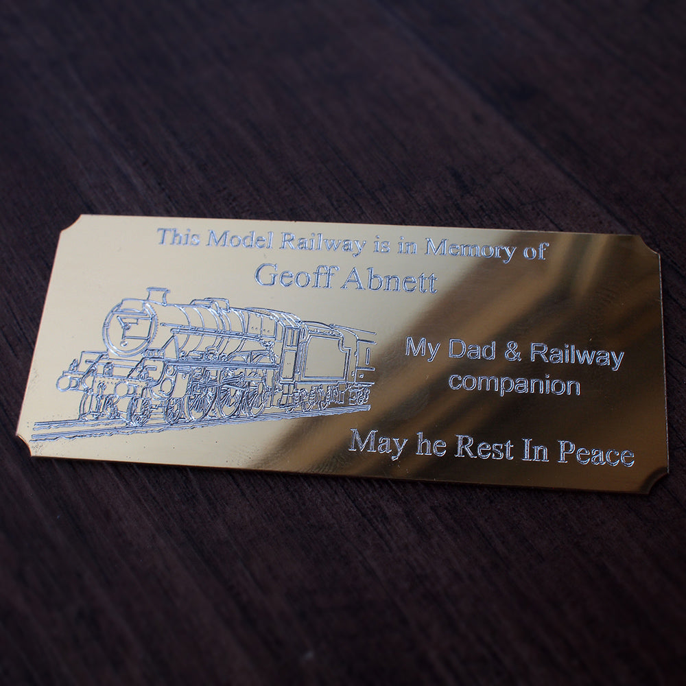 Gold memorial plaque for a model railway, including steam train artwork and text