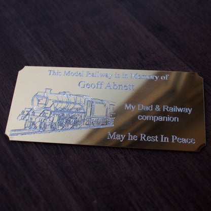 Gold memorial plaque for a model railway, including steam train artwork and text