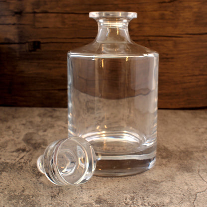 round glass spirits decanter with round stopper removed and displayed in front of the decanter